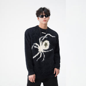 Person wearing a black sweater with a white spider design on a plain background