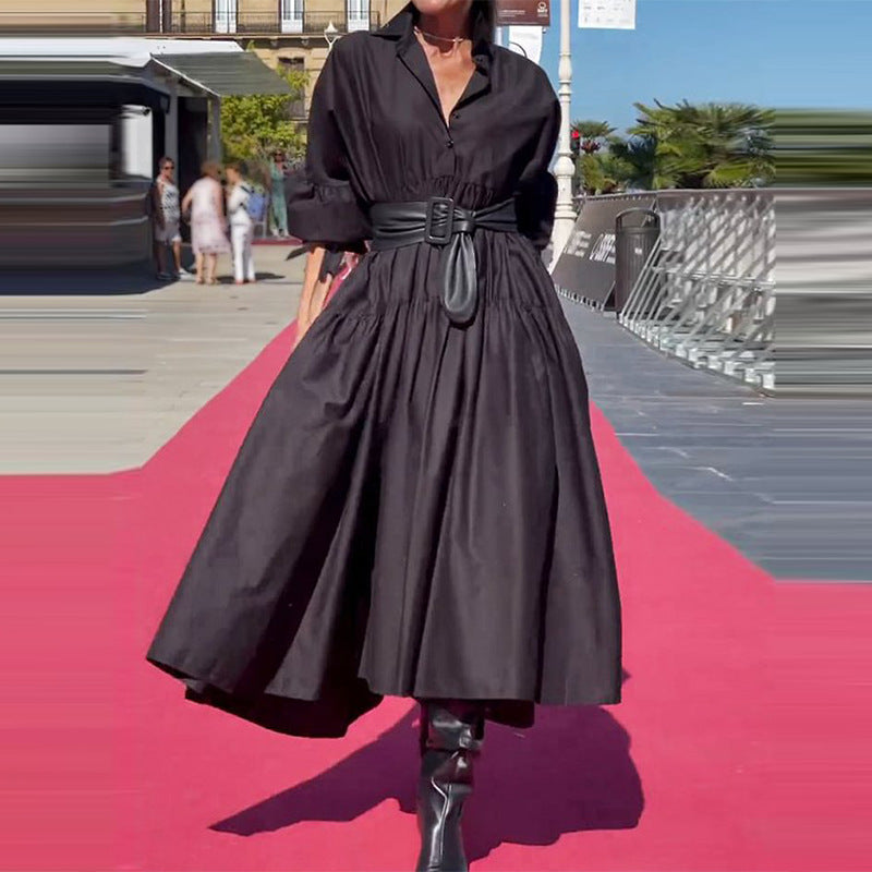 Person wearing a black dress on a red carpet with blurred background