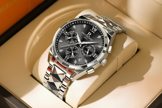 Silver watch with black dial on a beige surface, featuring a tag with text.