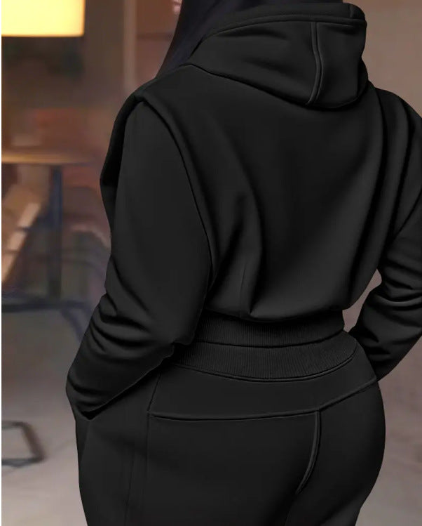 Person wearing a black hoodie and pants in an indoor setting