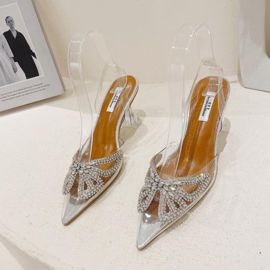 Silver high-heeled shoes with clear straps on a white surface