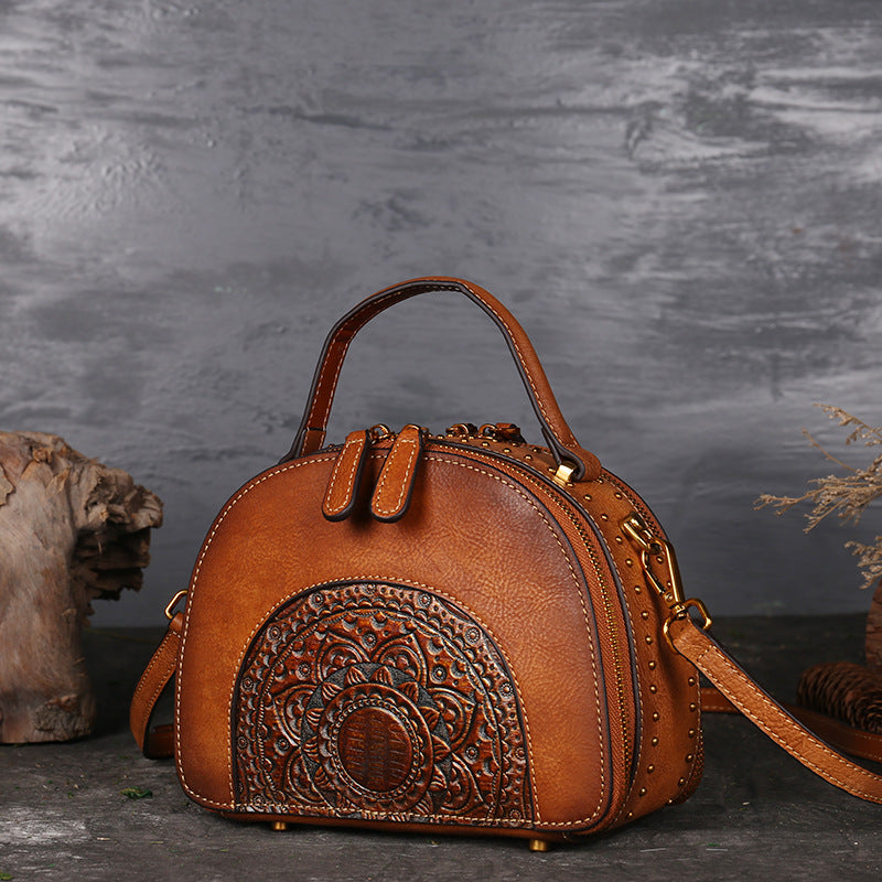 Brown leather handbag with intricate design on a dark background