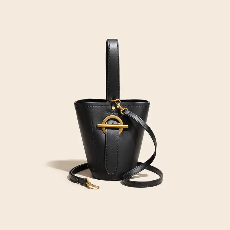 Black handbag with gold accents on a beige background