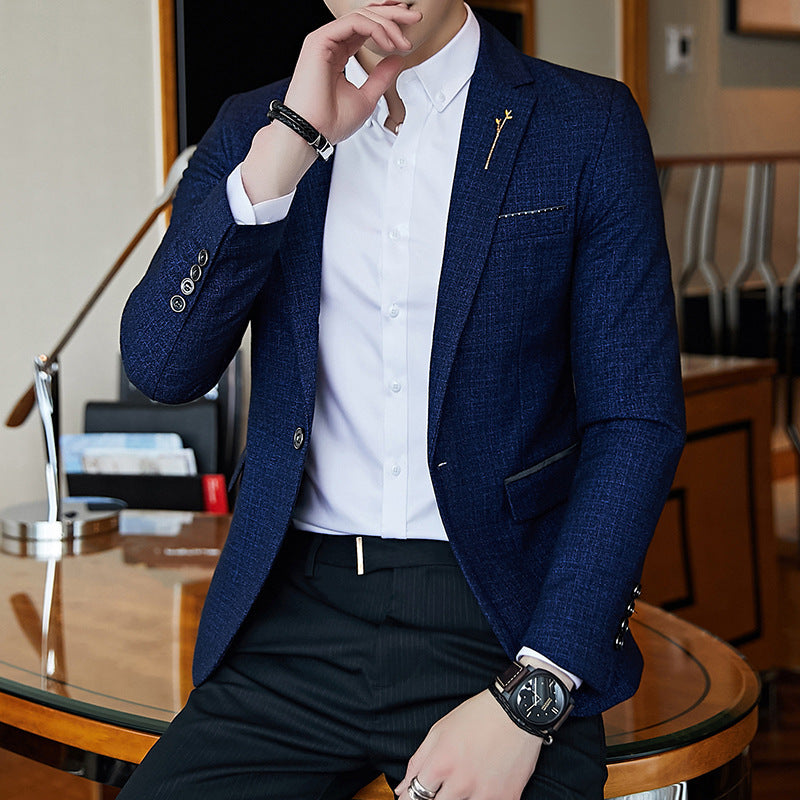 Man wearing a blue blazer over a white shirt, sitting in an indoor setting.