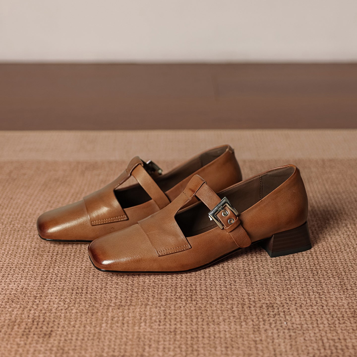 Pair of brown leather shoes with buckles on a textured surface
