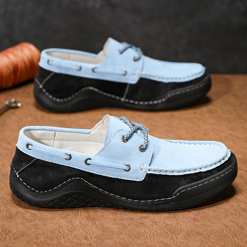 Pair of black and light blue loafers on a brown surface with a dark background.