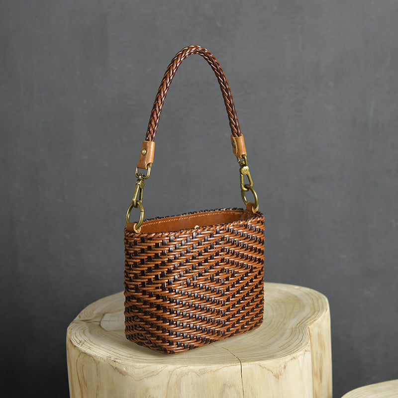 Woven handbag with braided handle on a wooden block against a dark background