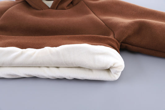 Brown and white hoodie folded on a gray surface