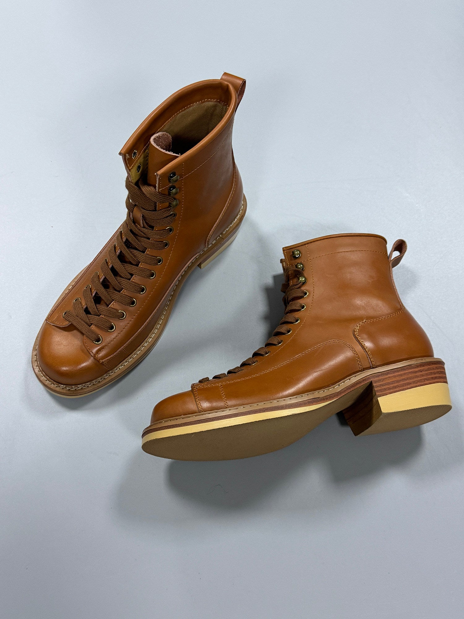 Pair of brown leather boots on a light gray background