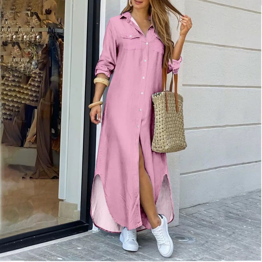 Woman wearing a pink dress with a slit, holding a straw bag, standing outside a store.
