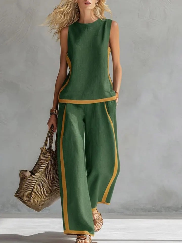 Woman wearing a green outfit with yellow accents, holding a woven bag against a gray background