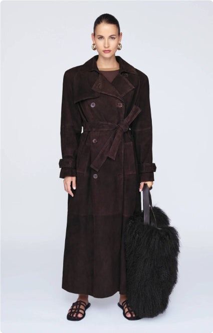 Woman wearing a long brown coat holding a black fur bag on a white background by Millivan 