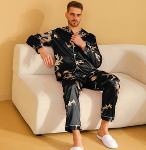 Man wearing a black pajama set with white floral patterns, sitting on a white couch.