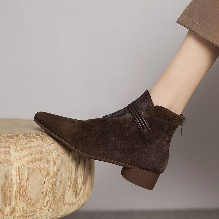 Brown suede ankle boot on a wooden stool with a neutral background