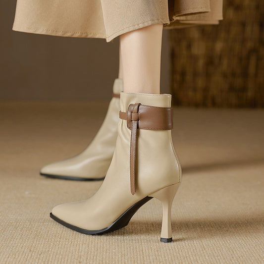 Beige ankle boots with brown strap on a beige background