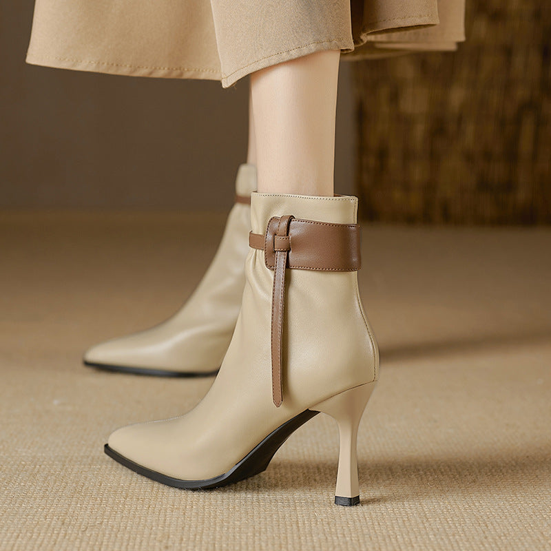 Beige ankle boots with brown strap on a beige background