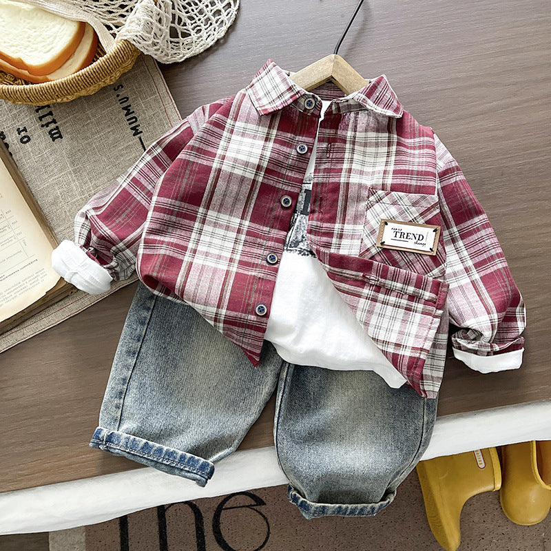 Children's outfit with plaid shirt and jeans on a wooden surface