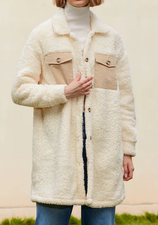 Person wearing a cream sherpa coat with beige accents against a neutral background
