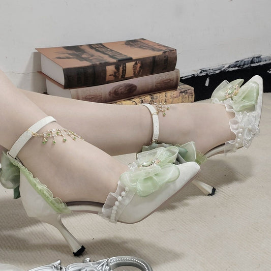 Green high-heeled shoes with floral details on a neutral background