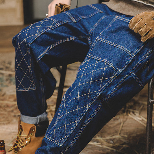 Person wearing blue jeans with intricate stitching detail, sitting on a chair.