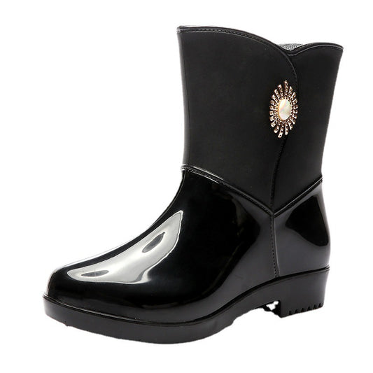 Black rain boot with a decorative emblem on a white background