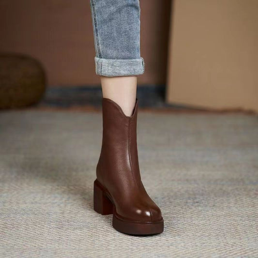 Brown ankle boot worn with rolled-up jeans on a neutral background