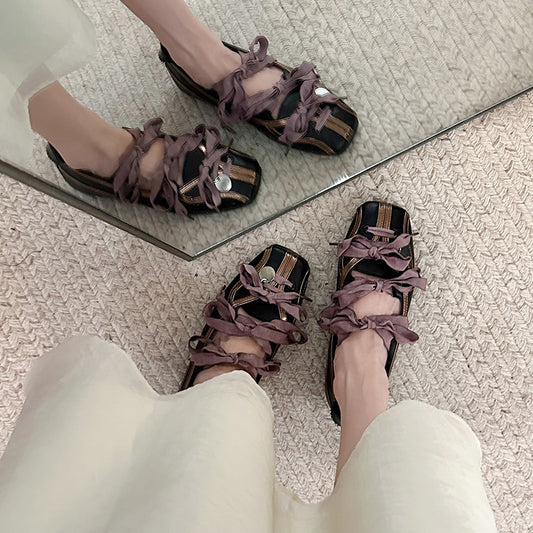 Pair of strappy sandals worn indoors with a mirror reflection.