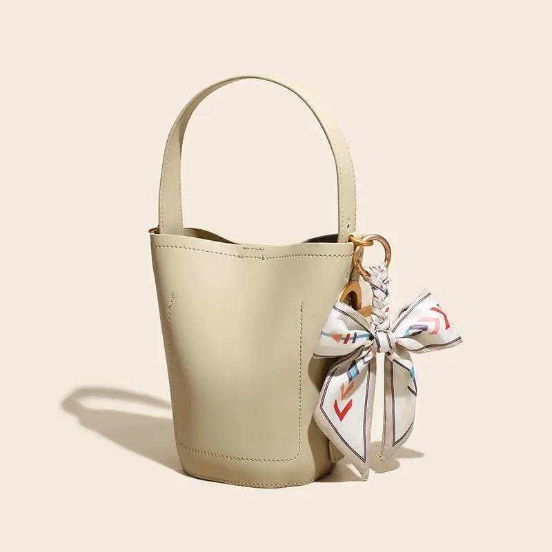 Beige handbag with a decorative bow on a beige background