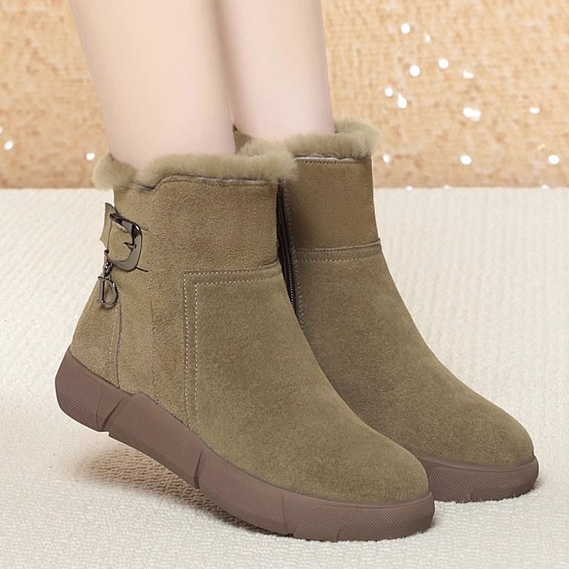 Green ankle boots with brown soles on a neutral background