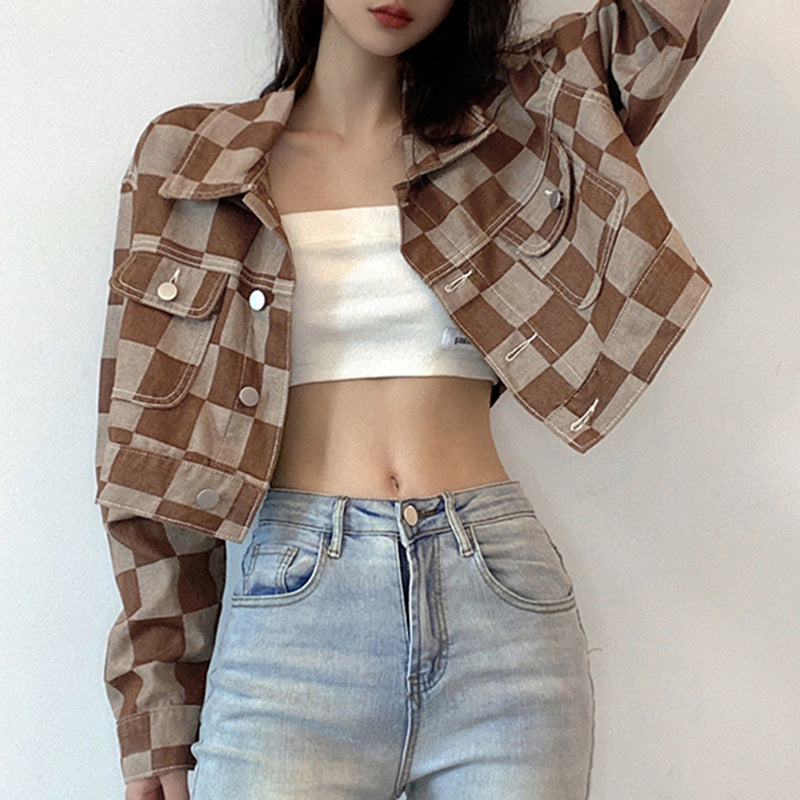 Person wearing a brown and beige checkered jacket, white top, and blue jeans against a white background