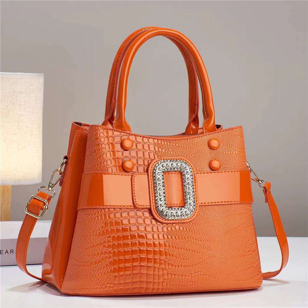 Orange handbag with a decorative buckle on a neutral background
