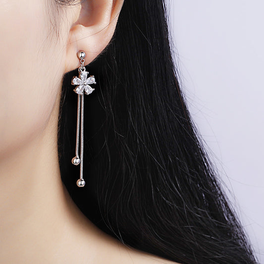 Silver earrings with floral design worn by a person with black hair.