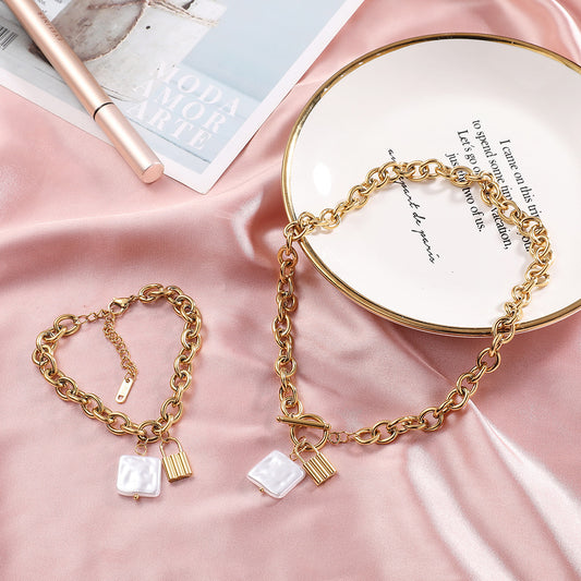 Gold chain bracelets with square charms on a pink fabric background