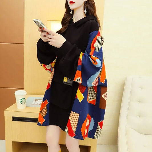 Woman wearing a black dress with colorful geometric patterned cardigan in a room.