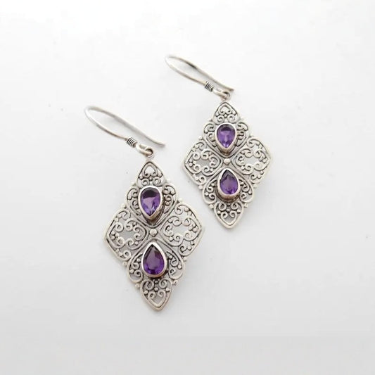 Silver earrings with purple gemstones on a white background