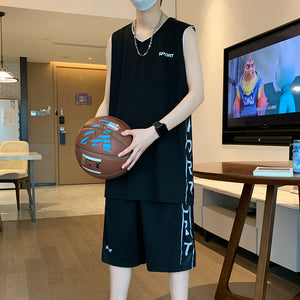 Person wearing a black sleeveless shirt and shorts holding a basketball in a room with a TV in the background.