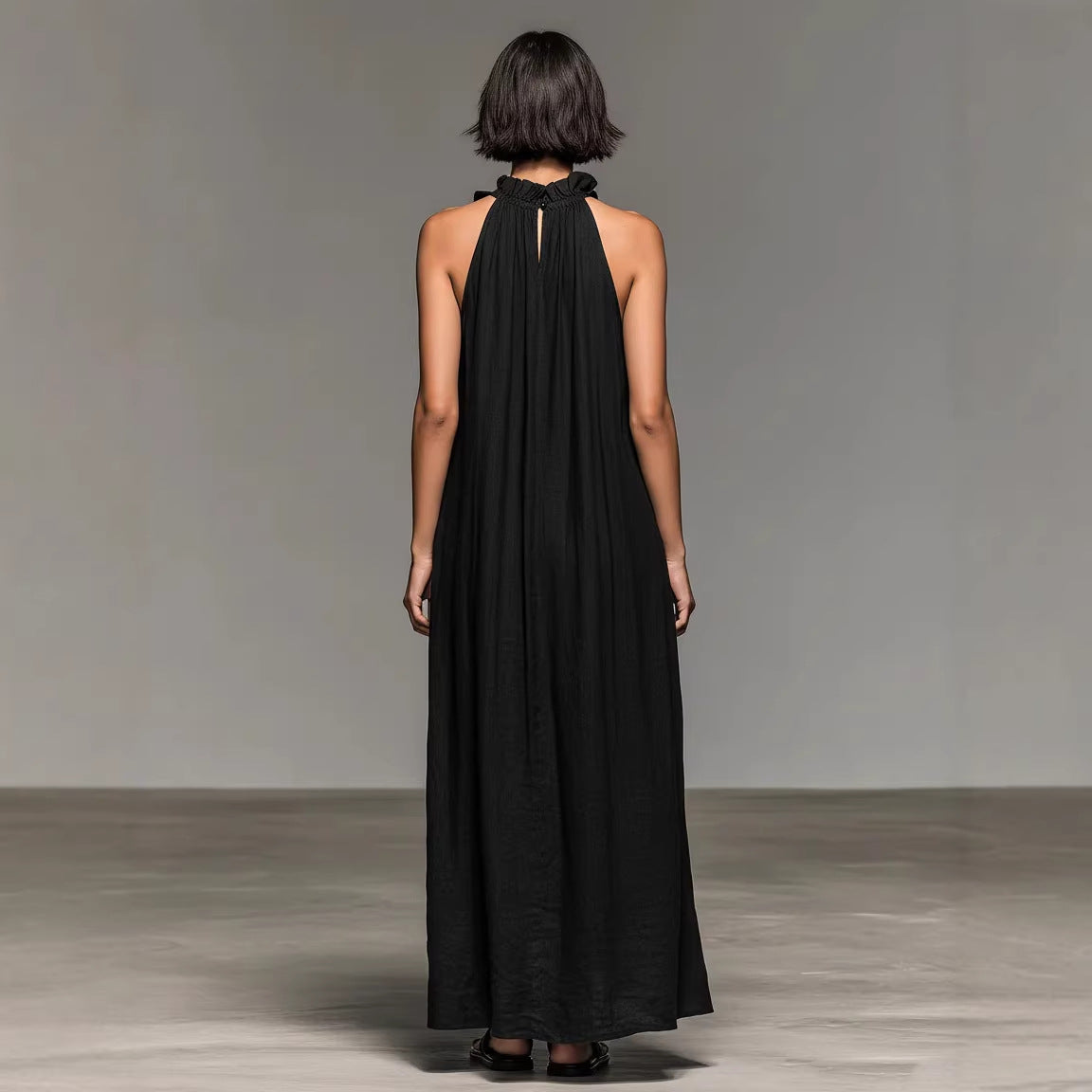Woman wearing a black halter neck dress against a plain background by millivan
