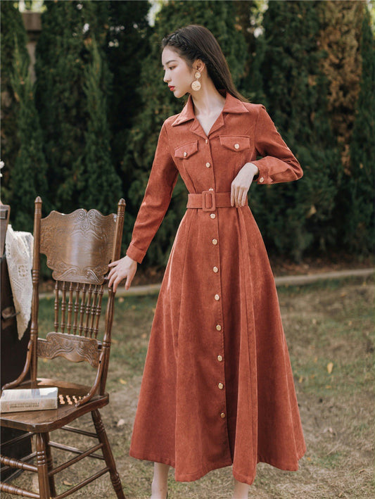 Woman in a rust-colored dress standing outdoors with greenery in the background by millivan