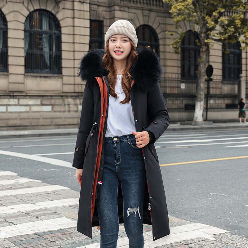 Woman wearing a long black coat with a fur-lined hood on a city street.