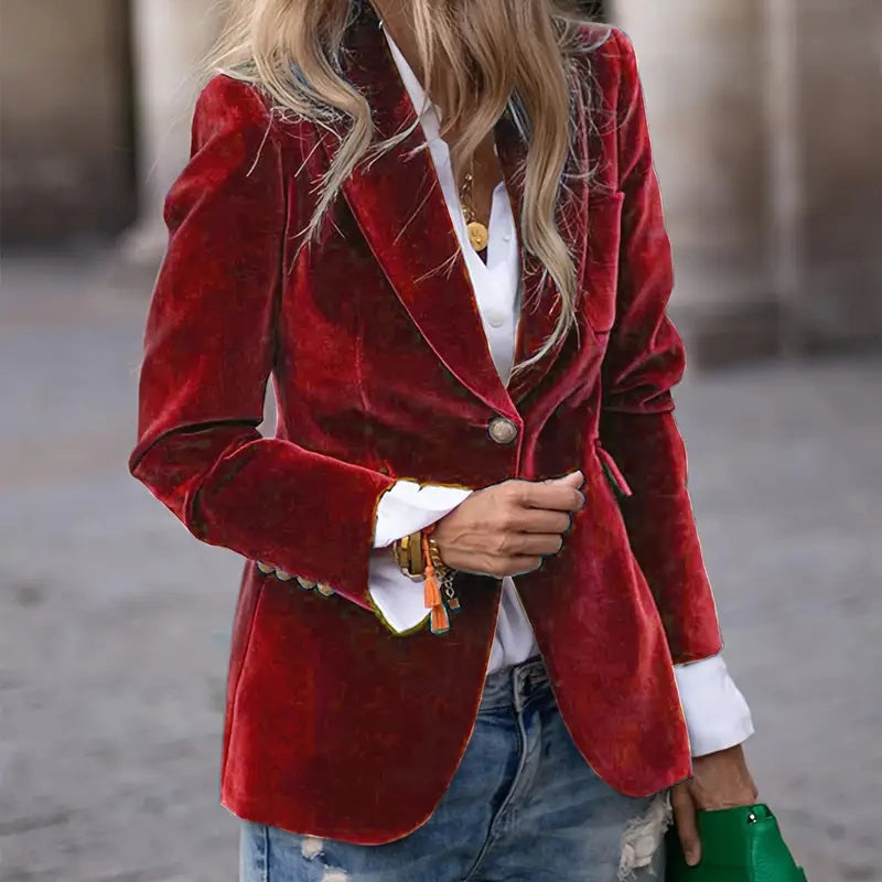 Person wearing a red velvet blazer over a white shirt with a blurred background
