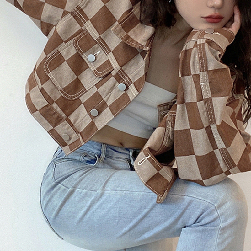 Person wearing a brown and beige checkered jacket with light blue jeans on a white background