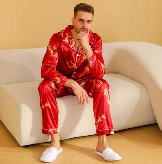 Man wearing red pajamas with gold patterns sitting on a white couch.