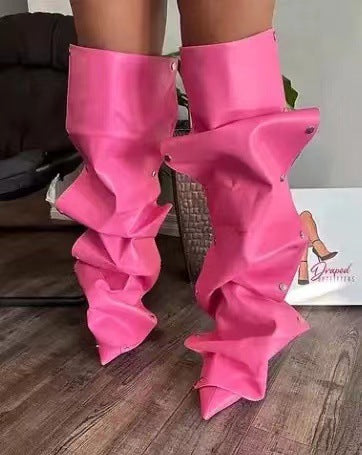 Pink ruffled leg warmers worn by a person on a wooden floor.