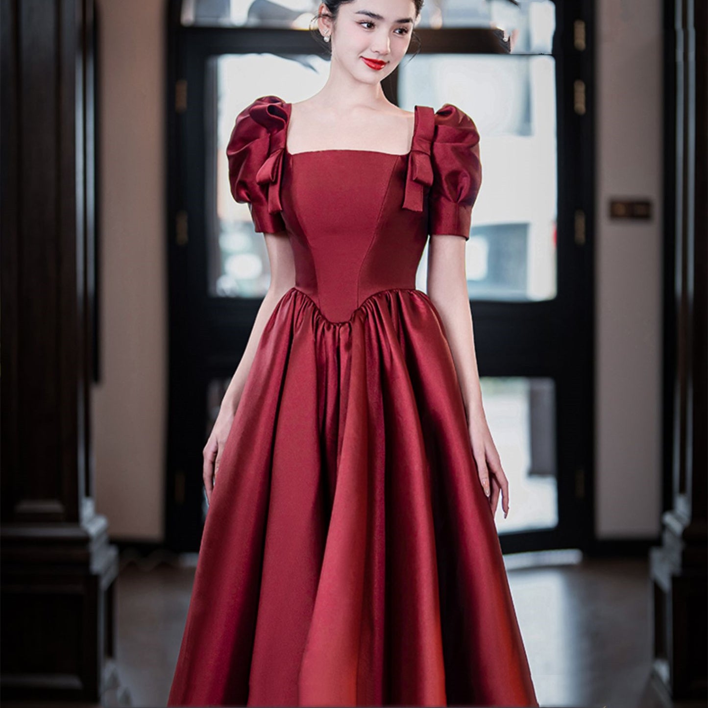 Woman wearing a red dress with puff sleeves in an indoor setting