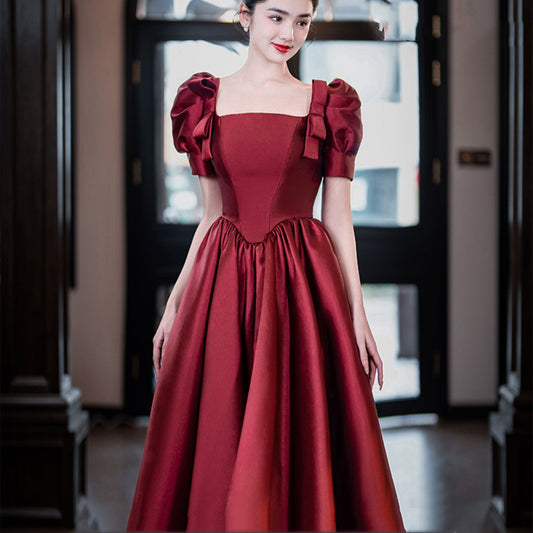 Woman wearing a red dress with puff sleeves in an indoor setting