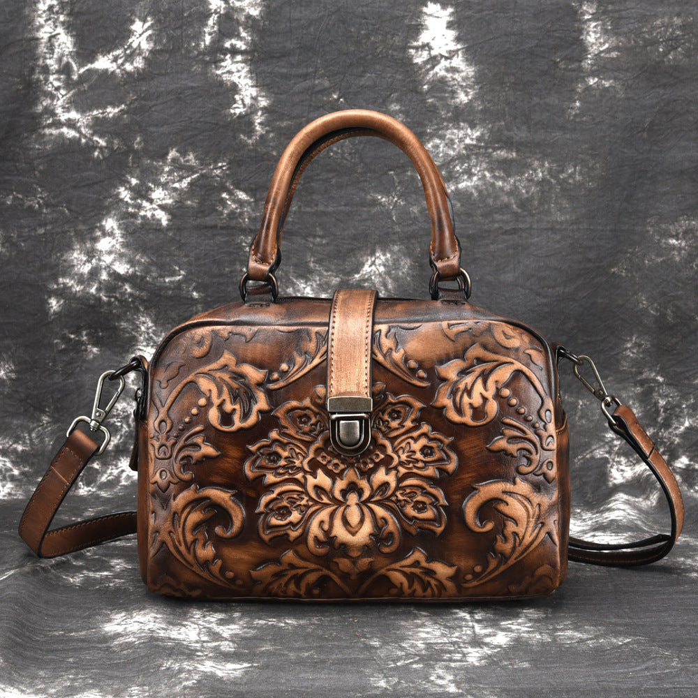 Brown leather handbag with intricate patterns on a textured gray background