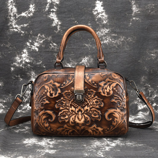 Brown leather handbag with intricate patterns on a textured gray background