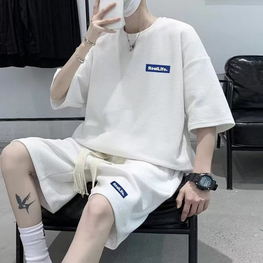 Person wearing a white outfit with 'RealLife' branding, sitting on a chair.