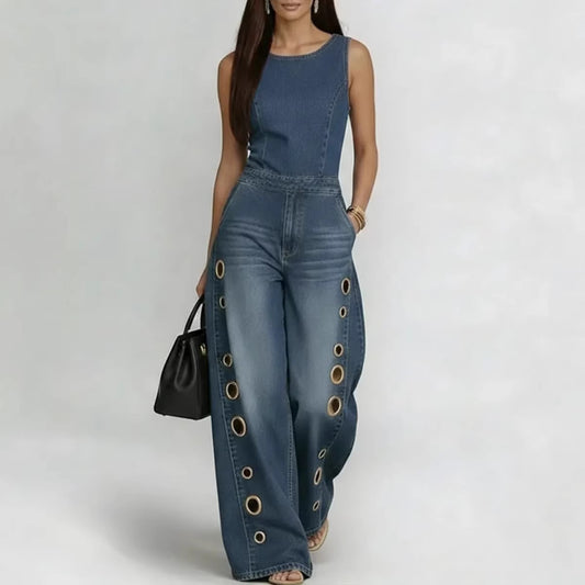 Woman wearing a blue denim jumpsuit with grommet details on a white background