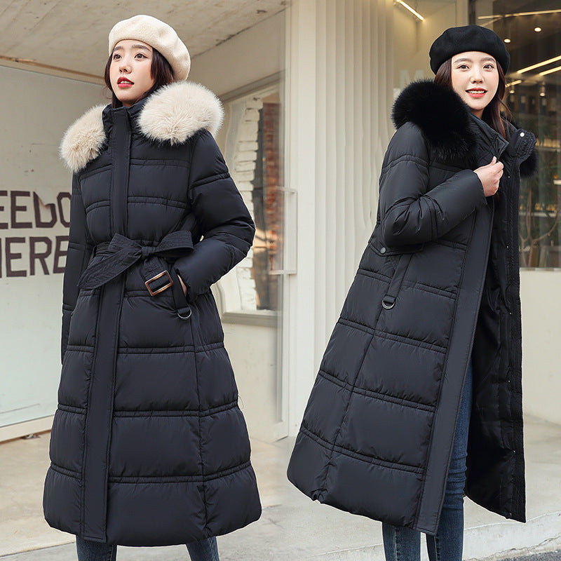 Two women wearing long black puffer coats with fur-lined hoods in an urban setting.